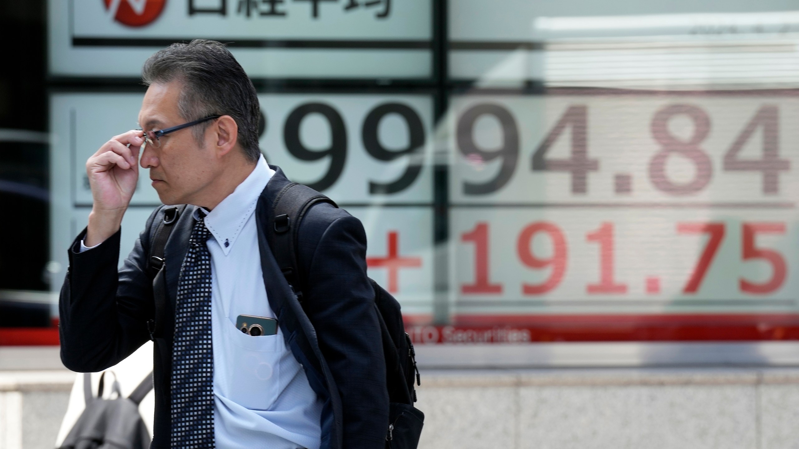 A person walks in front of an electronic stock board showing Japan's Nikkei 225 index at a securities firm Tuesday, April 2, 2024, in Tokyo. Asian shares were mixed on Tuesday after Wall Street pulled back from its record following a shaky day of trading, putting at least a temporary halt to its huge rally since Halloween. (AP Photo/Eugene Hoshiko)