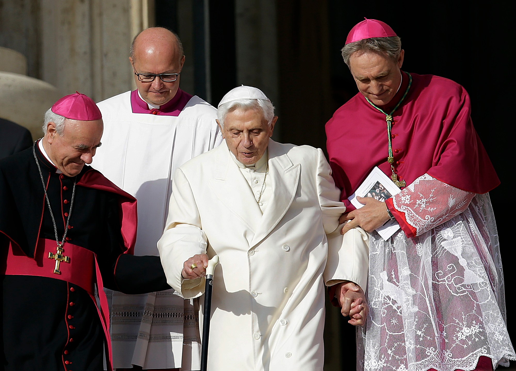FILE - Pope Emeritus Benedict XVI, center, is helped to walk down the steps by Bishops Vincenzo Paglia, left, and Georg Gaenswein prior to the start of a meeting of Pope Francis with the elderly in St. Peter's Square at the Vatican, on Sept. 28, 2014. Pope Francis has exposed the political “maneuvers” to sway votes during the past two conclaves and denied he is planning to reform the process to elect a pope in a new book-length interview published Tuesday April 2, 2024. (AP Photo/Gregorio Borgia, File)