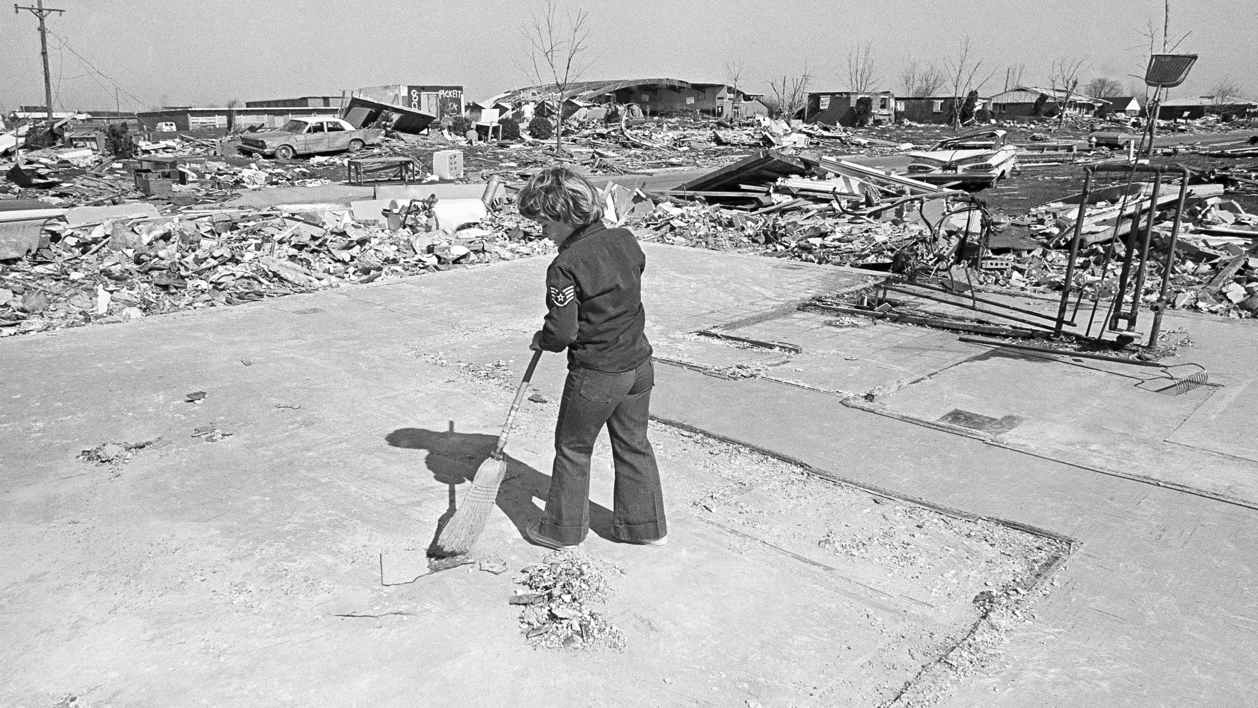 FILE - Mike Muney, 7, sweeps off the slab of a neighbor's house that was demolished by the early April 1974 storm in Xenia, Ohio, April 19, 1974. The deadly tornado killed 32 people, injured hundreds and leveled half the city of 25,000. Nearby Wilberforce was also hit hard. As the Watergate scandal unfolded in Washington, President Richard Nixon made an unannounced visit to Xenia to tour the damage. Xenia's was the deadliest and most powerful tornado of the 1974 Super Outbreak. (AP Photo, file)