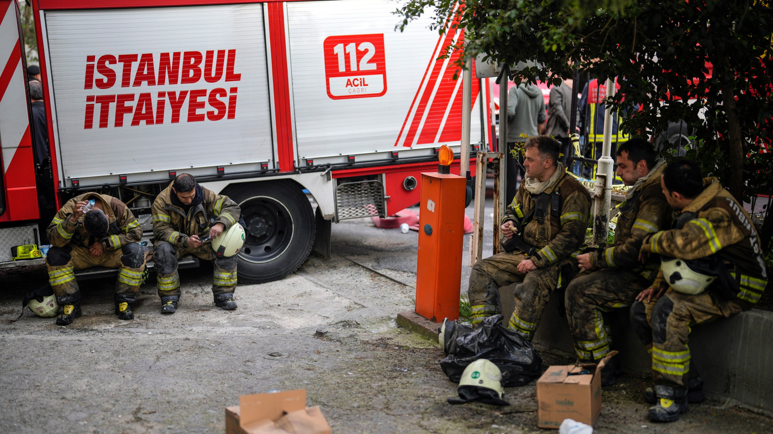 Firefighters rest in the aftermath of a fire in a nightclub in Istanbul, Turkey, Tuesday, April 2, 2024. A fire at an Istanbul nightclub during renovations on Tuesday killed at least 29 people, officials and reports said. Several people, including managers of the club, were detained for questioning. (AP Photo/Khalil Hamra)