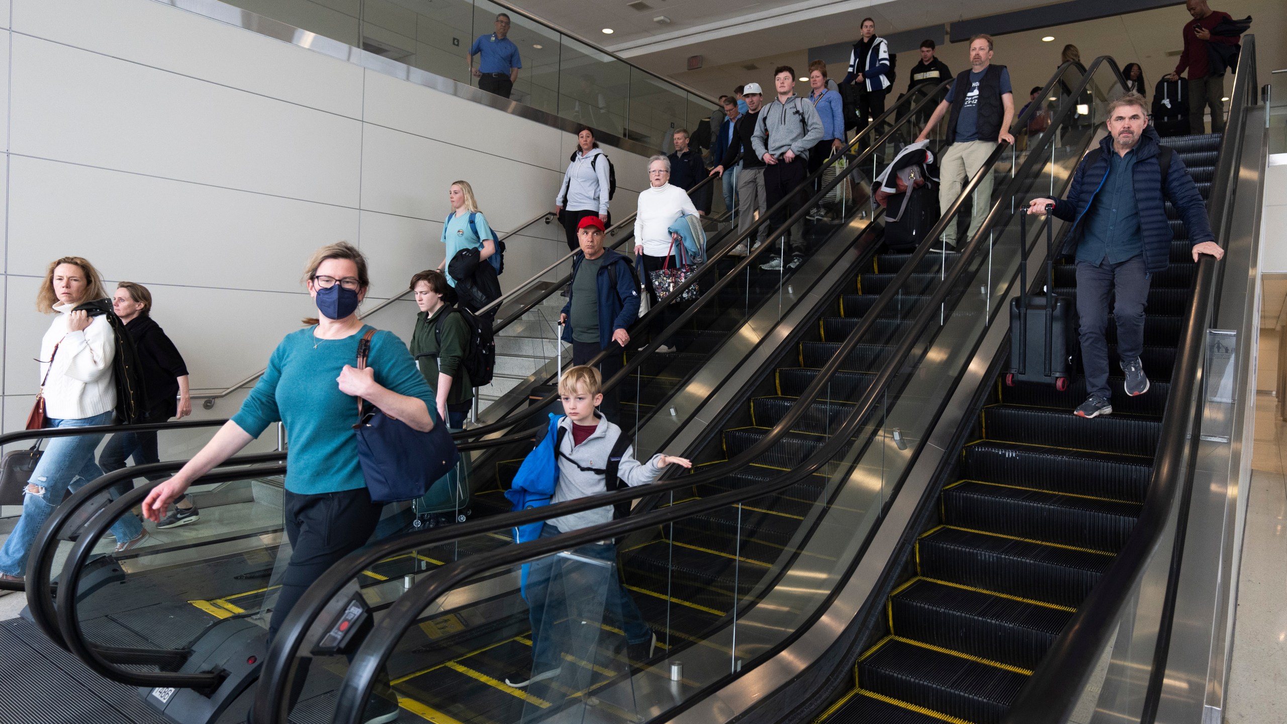 International travelers go down the escalator to get processed at the port of entry at Washington Dulles International Airport in Chantilly, Va. Monday, April 1, 2024. (AP Photo/Manuel Balce Ceneta)