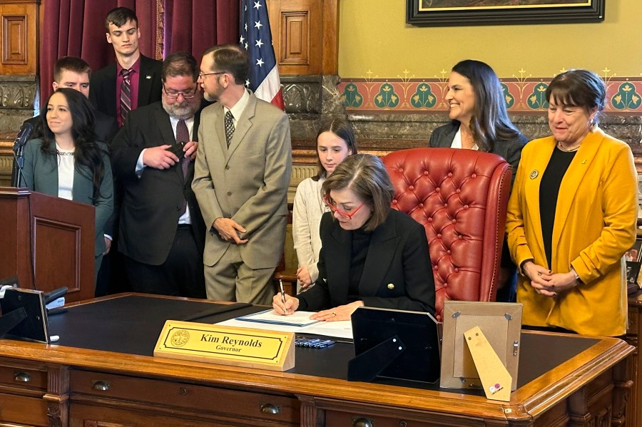 Iowa Gov. Kim Reynolds signs a bill repealing an explicit requirement that Iowa's state, county and local decision-making bodies be balanced by gender, Wednesday, April 3, 2024, in Des Moines, Iowa. Before signing the repeal bill into law, Reynolds said the focus for boards and commissions “should always be on appointing the most qualified people.” (AP Photo/Hannah Fingerhut)