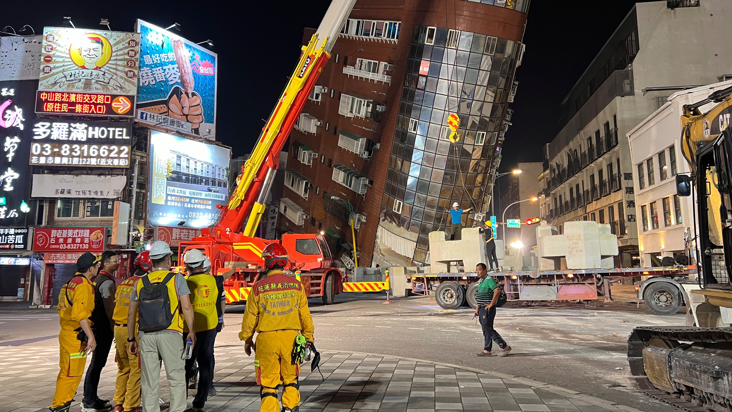 Rescue workers stand near the site of a leaning building in the aftermath of an earthquake in Hualien, Taiwan, on Wednesday, April 3, 2024. Taiwan's strongest earthquake in a quarter century rocked the island during the morning rush hour Wednesday. (AP Photo/Johnson Lai)