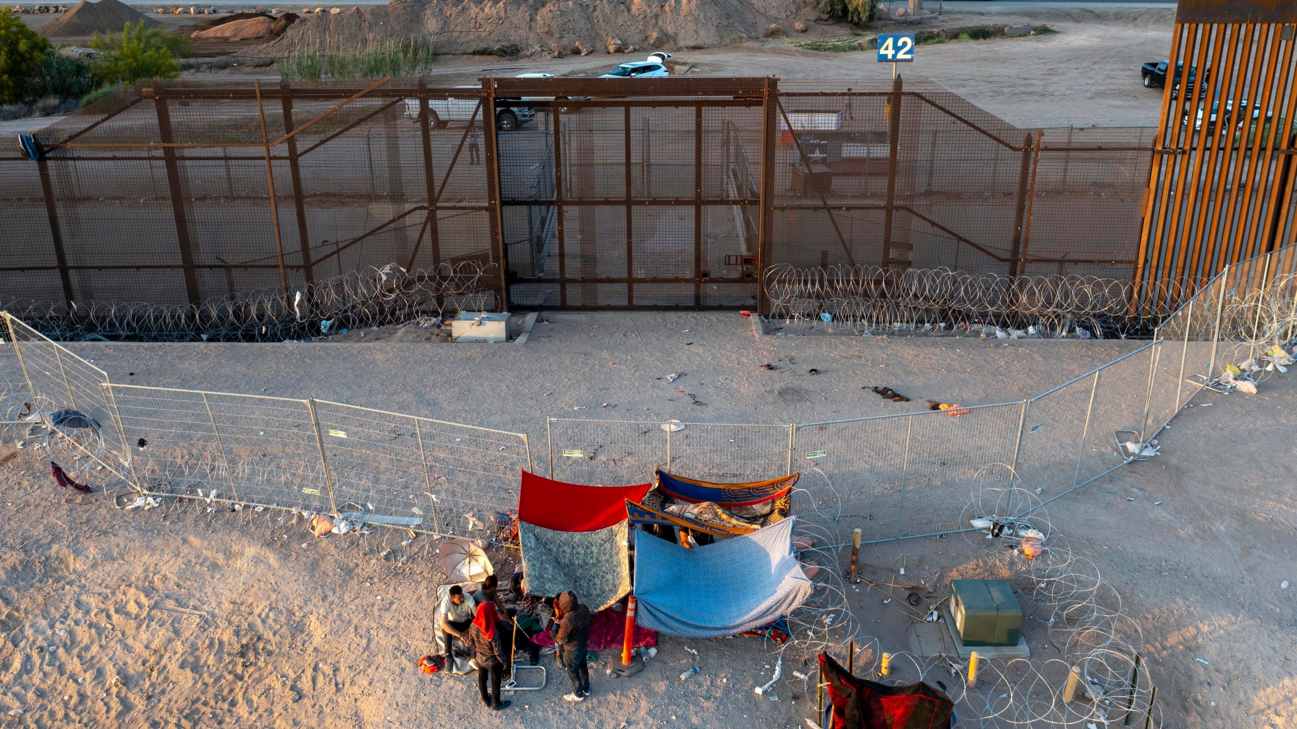 FILE - A small group of migrants are pictured while camping outside a gate in the border fence in El Paso, Texas, Friday, May 12, 2023. Migrant children in makeshift camps along the U.S.-Mexico border who are waiting to be processed by Border Patrol are in the agency's custody _ something the agency had denied _ and said the Department of Homeland Security must quickly process them and place them in facilities that are “safe and sanitary.” (AP Photo/Andres Leighton, File)