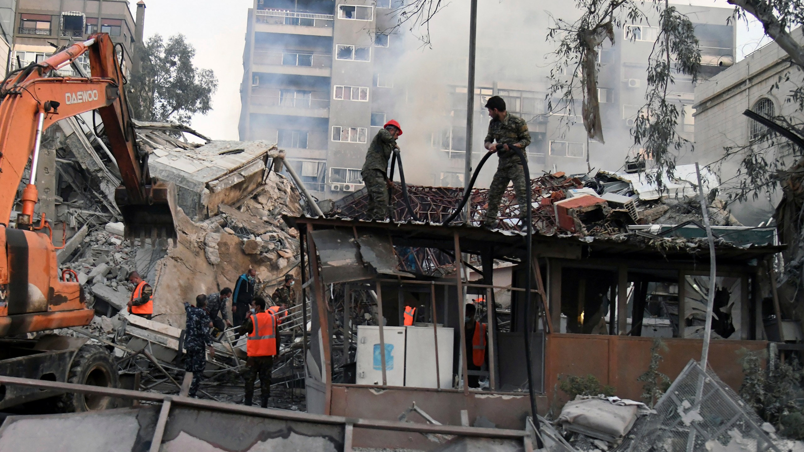 In this photo released by the official Syrian state news agency SANA, emergency service workers clear the rubble at a destroyed building struck by Israeli jets in Damascus, Syria, Monday, April 1, 2024. An Israeli airstrike has destroyed the consular section of Iran's embassy in Syria, killing a senior Iranian military adviser and roughly a handful of other people, Syrian state media said Monday. (SANA via AP)