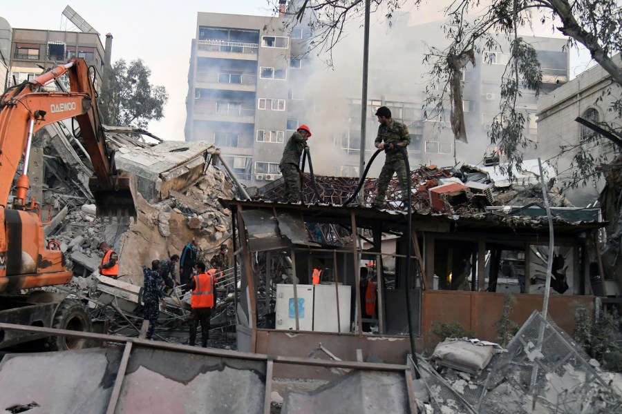 In this photo released by the official Syrian state news agency SANA, emergency service workers clear the rubble at a destroyed building struck by Israeli jets in Damascus, Syria, Monday, April 1, 2024. An Israeli airstrike has destroyed the consular section of Iran's embassy in Syria, killing a senior Iranian military adviser and roughly a handful of other people, Syrian state media said Monday. (SANA via AP)