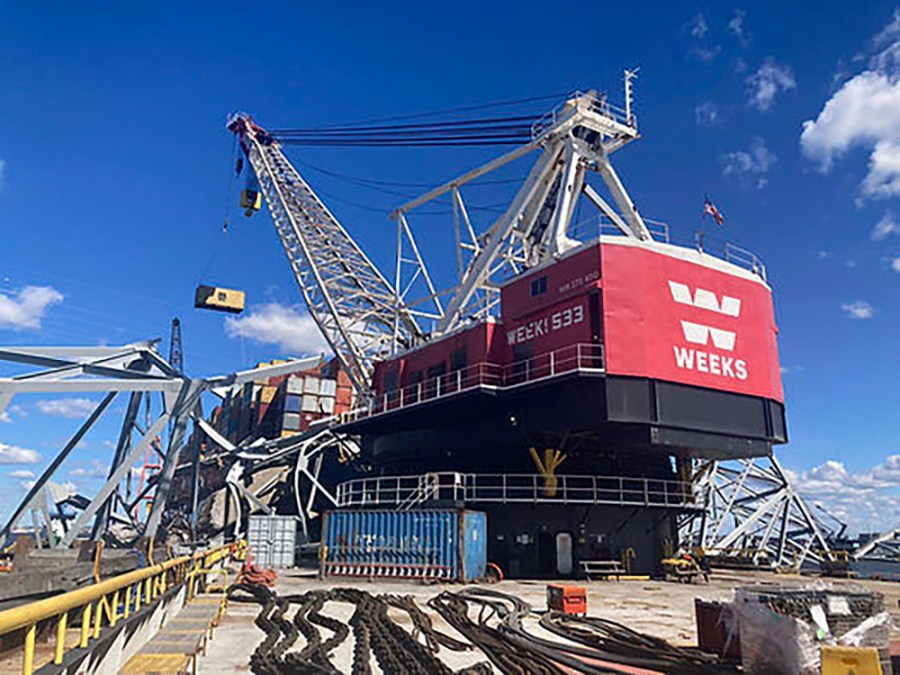 In this photo provided by the Key Bridge Response 2024 Unified Command, response crews begin removing shipping containers from the deck of the cargo ship Dali using a floating crane barge at the site of the Francis Scott Key Bridge, Sunday, April 7, 2024, in Baltimore. (Key Bridge Response 2024 Unified Command via AP)