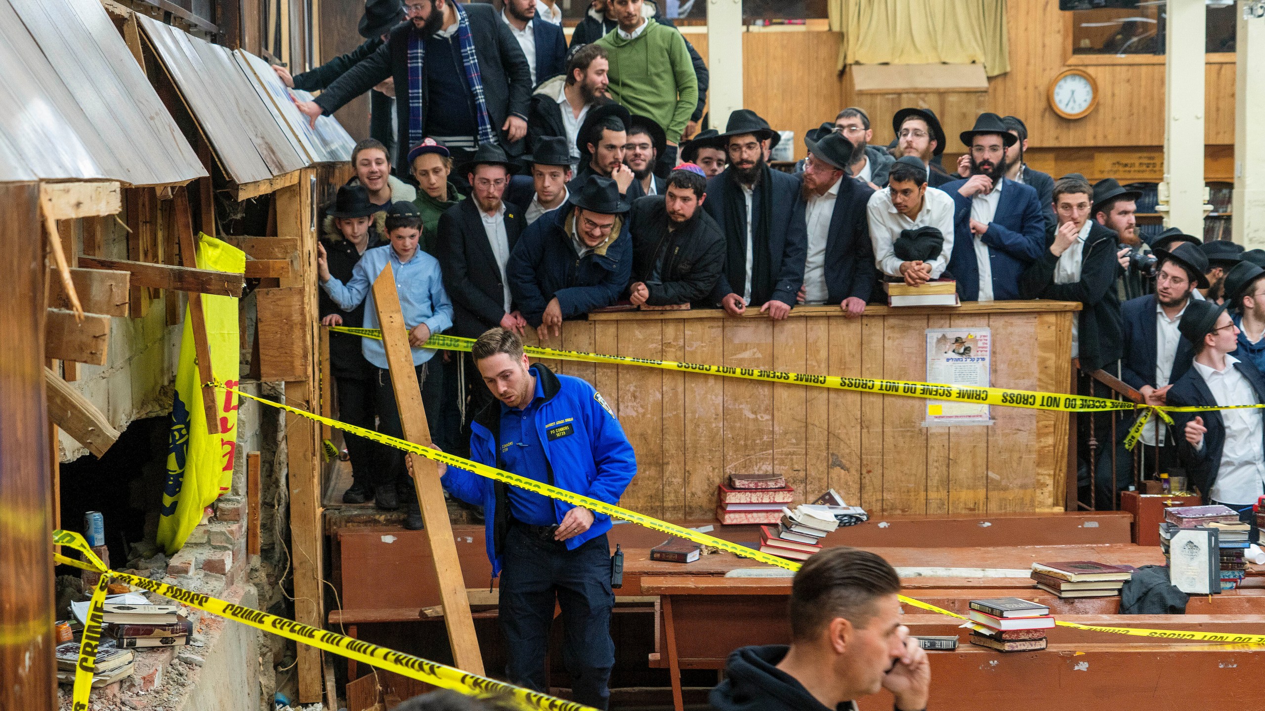 FILE - Hasidic Jewish students observe as law enforcement establishes a perimeter around a breached wall in the synagogue that led to a tunnel dug by students, Jan. 8, 2024, in New York. Thirteen members of the Hasidic Jewish community pleaded not guilty Wednesday, April 10, to charges stemming from their alleged role in a dispute over an illegal tunnel built beneath a historic Brooklyn synagogue. (Bruce Schaff via AP, File)