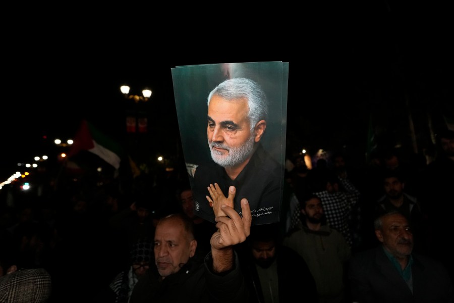 A demonstrator holds up a poster of the late Iranian Revolutionary Guard Gen. Qassem Soleimani, who was killed in a U.S. drone attack in 2020 in Iraq, during an anti-Israeli gathering in front of the British Embassy in Tehran, Iran, early Sunday, April 14, 2024. Iran launched its first direct military attack against Israel on Saturday. (AP Photo/Vahid Salemi)