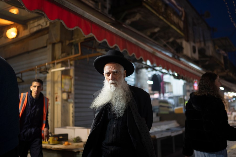 An elderly ultra-Orthodox Jewish man looks on as he walks in the Mahane Yehuda market in Jerusalem, Sunday, April 14, 2024. Israel on Sunday hailed its air defenses in the face of an unprecedented attack by Iran, saying the systems thwarted 99% of the more than 300 drones and missiles launched toward its territory. (AP Photo/Leo Correa)