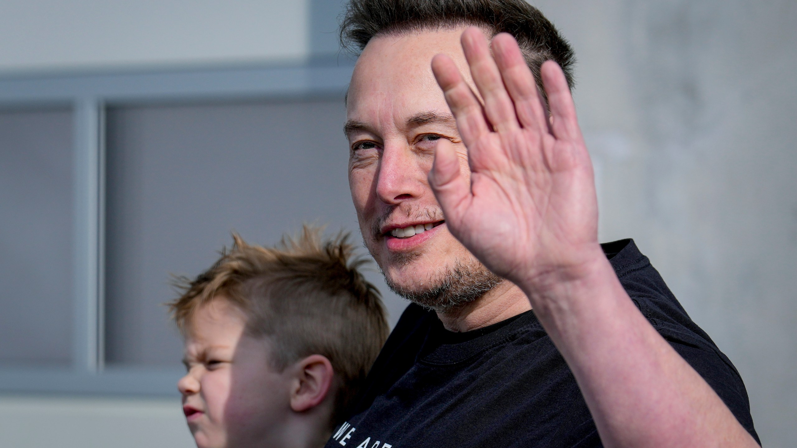 FILE - Tesla CEO Elon Musk waves as he leaves the Tesla Gigafactory for electric cars after a visit in Gruenheide near Berlin, Germany, March 13, 2024. After reporting dismal first-quarter sales, Tesla is planning to lay off about a tenth of its workforce as it tries to cut costs, multiple media outlets reported Monday. (AP Photo/Ebrahim Noroozi, File)