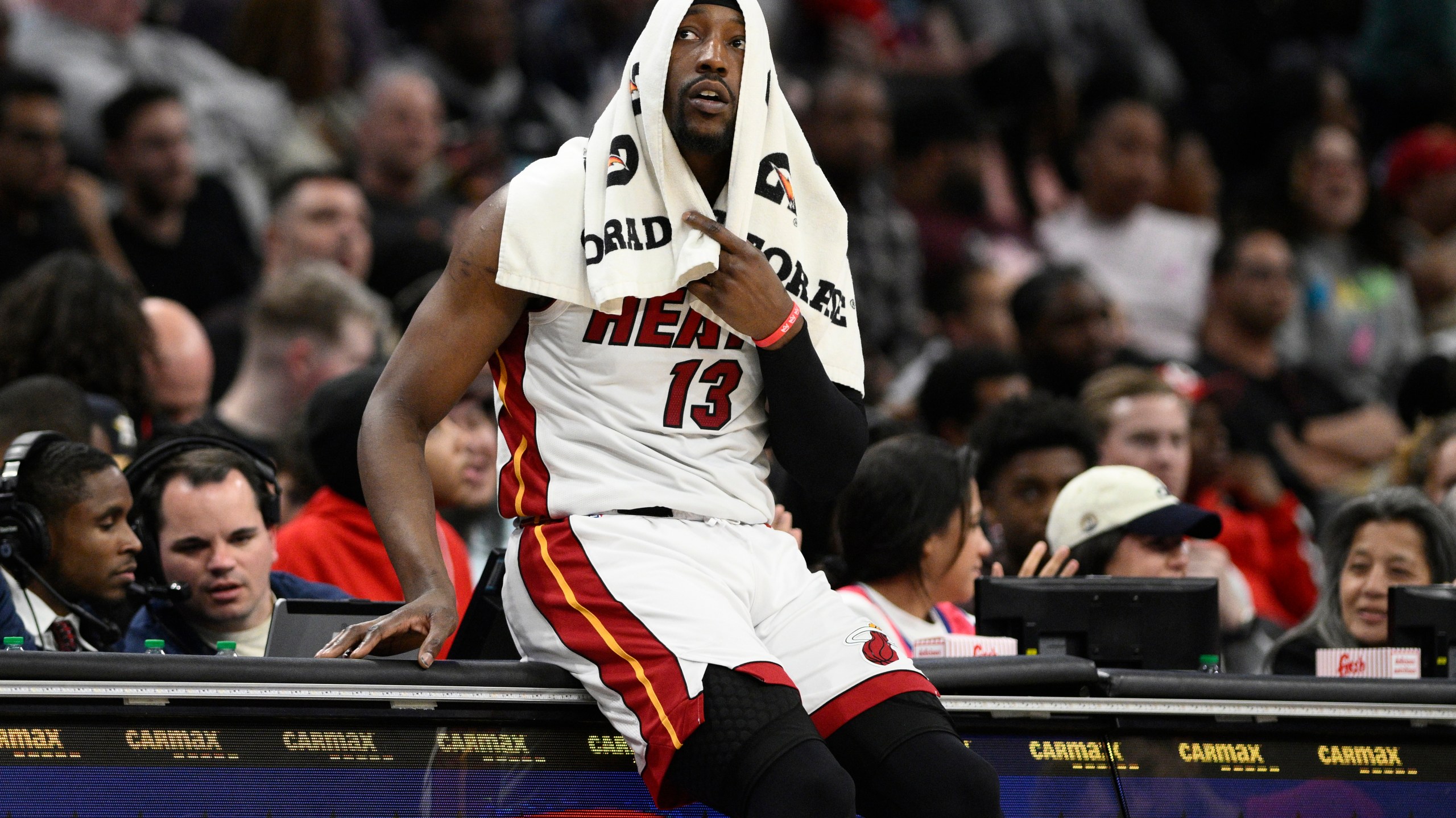 Miami Heat center Bam Adebayo (13) sits on the scorers table as he waits to enter the game during the second half of an NBA basketball game against the Washington Wizards, Sunday, March 31, 2024, in Washington. The Heat won 119-107. (AP Photo/Nick Wass)