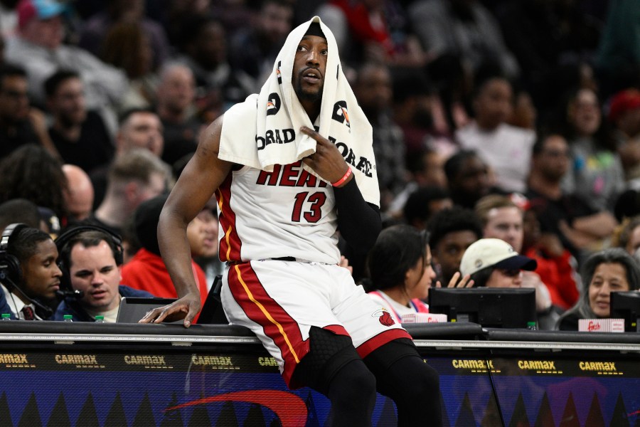 Miami Heat center Bam Adebayo (13) sits on the scorers table as he waits to enter the game during the second half of an NBA basketball game against the Washington Wizards, Sunday, March 31, 2024, in Washington. The Heat won 119-107. (AP Photo/Nick Wass)