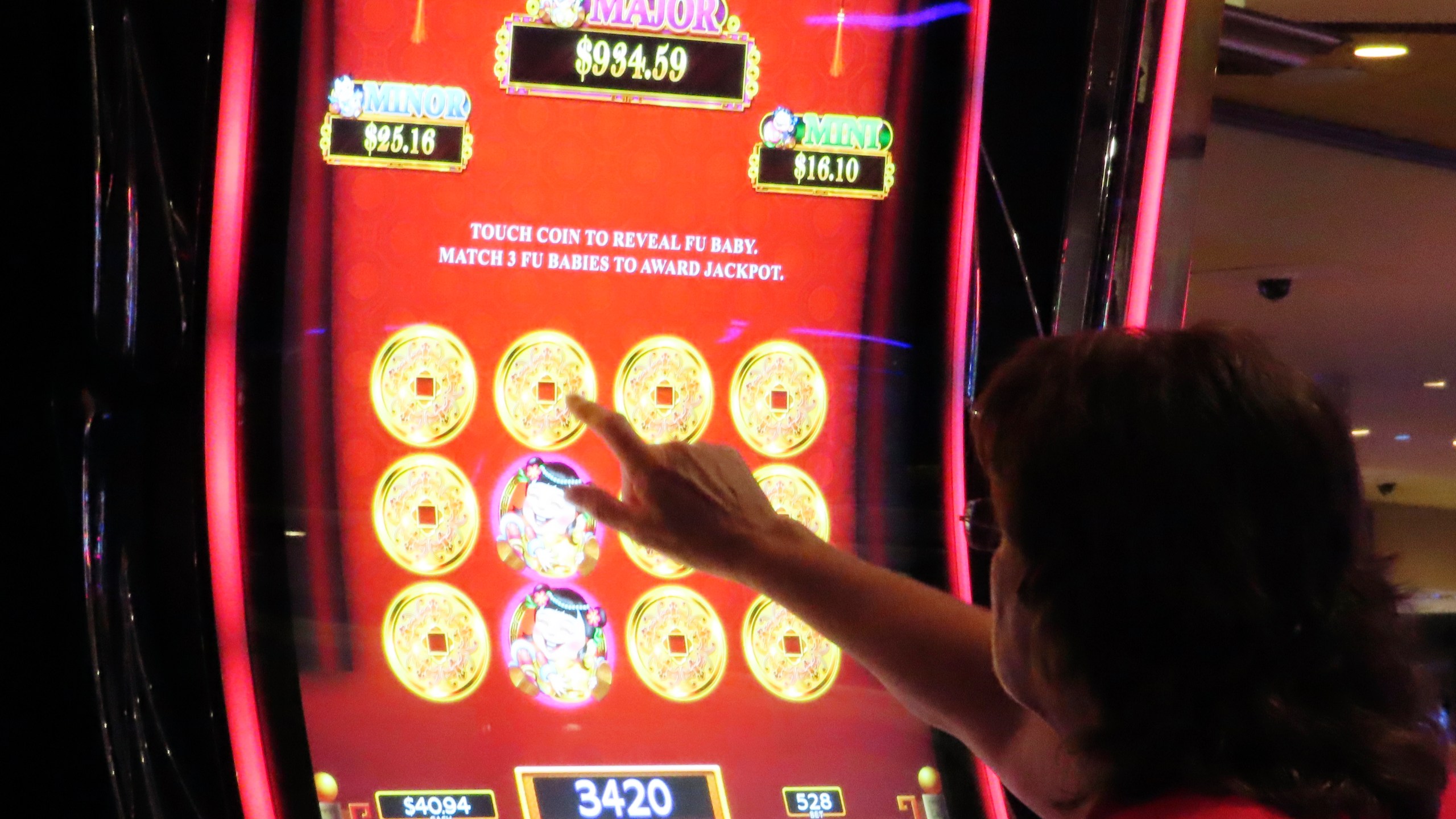 A gambler touches the screen of a slot machine at Harrah's casino in Atlantic City N.J., Sept. 29, 2023. Figures released, Tuesday, April 16, 2024, show Atlantic City's casinos, their online partners and horse tracks that take sports bets won over $526 million in March, a month in which New Jersey's internet gambling market set yet another monthly record at $197 million. (AP Photo/Wayne Parry)