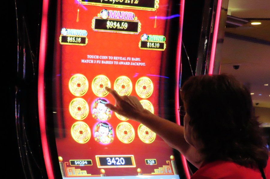 A gambler touches the screen of a slot machine at Harrah's casino in Atlantic City N.J., Sept. 29, 2023. Figures released, Tuesday, April 16, 2024, show Atlantic City's casinos, their online partners and horse tracks that take sports bets won over $526 million in March, a month in which New Jersey's internet gambling market set yet another monthly record at $197 million. (AP Photo/Wayne Parry)