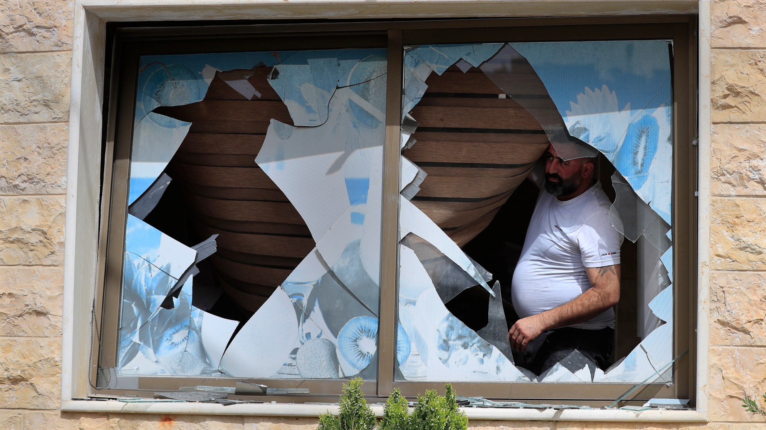 A Lebanese villager looks through a broken window of his house which was damaged by Israeli shelling, in Kfar Kila, a Lebanese border village with Israel, south Lebanon, Thursday, April 18, 2024. Hezbollah militants and Israeli forces have been exchanging fire since a day after the Israel-Hamas war began on Oct. 7. (AP Photo/Mohammed Zaatari)