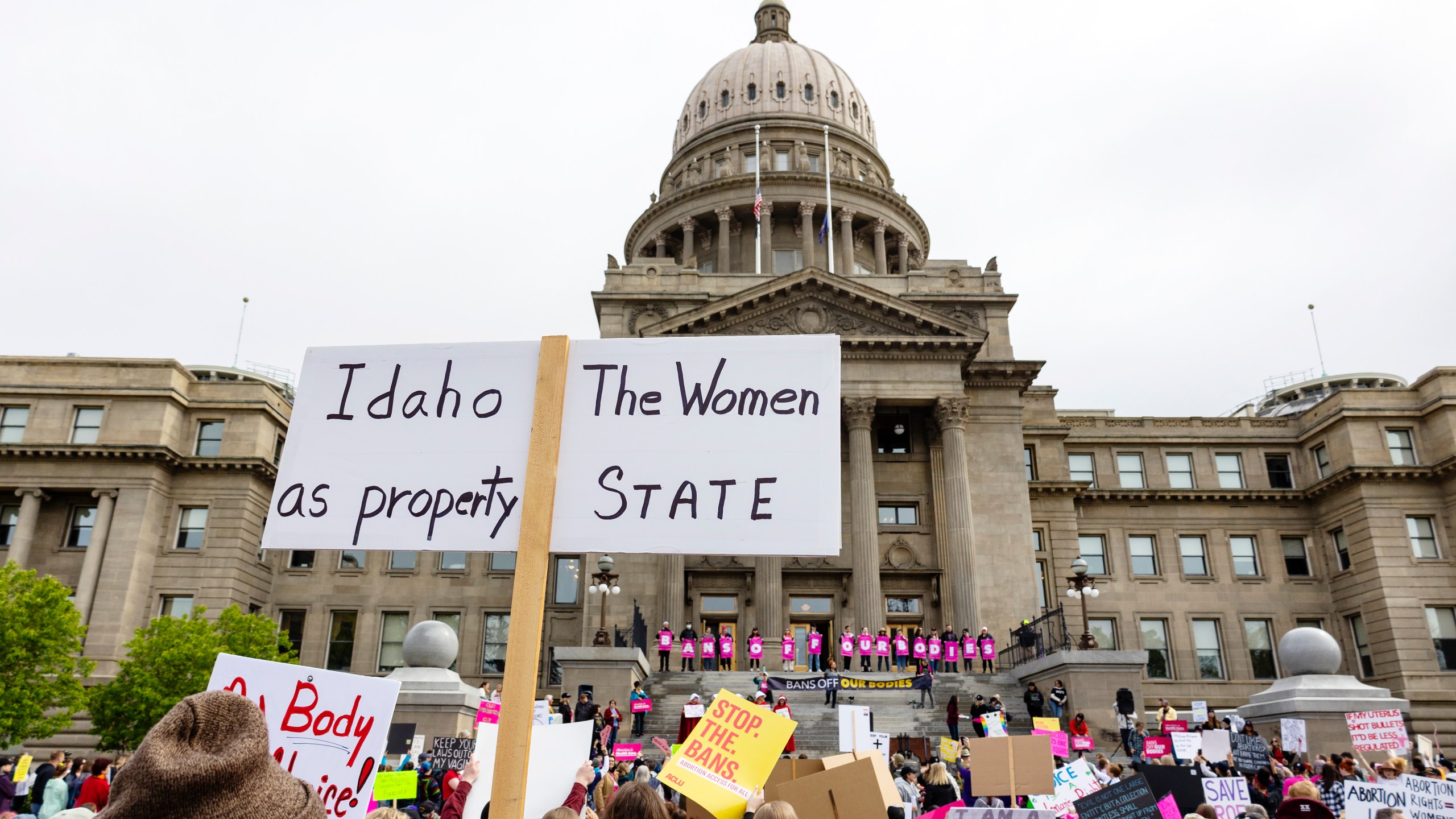 FILE - An attendee at Planned Parenthood's Bans Off Our Bodies rally for abortion rights holds a sign reading "Idaho the women as property state" outside of the Idaho Statehouse in downtown Boise, Idaho, on May 14, 2022. A new Idaho organization says it will ask voters to restore abortion access and other reproductive health care rights in the state after lawmakers let a second legislative session end without modifying strict abortion bans that have been blamed for a recent exodus of health care providers. . (Sarah A. Miller/Idaho Statesman via AP, File)