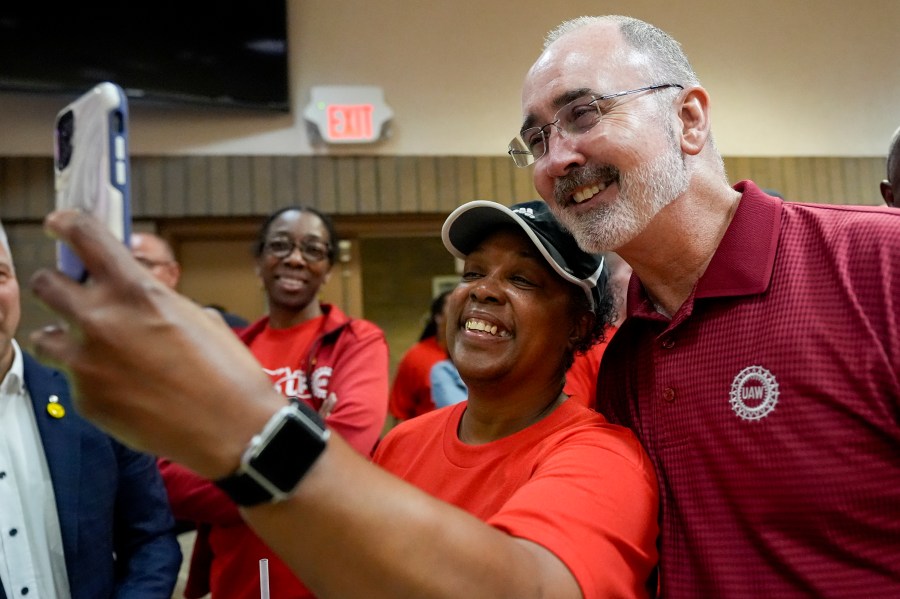 Volkswagen automobile plant employee LaShawn Hawthorne, center left, takes picture with UAW president Shawn Fain after workers voted to join the union Friday, April 19, 2024, in Chattanooga, Tenn. (AP Photo/George Walker IV)