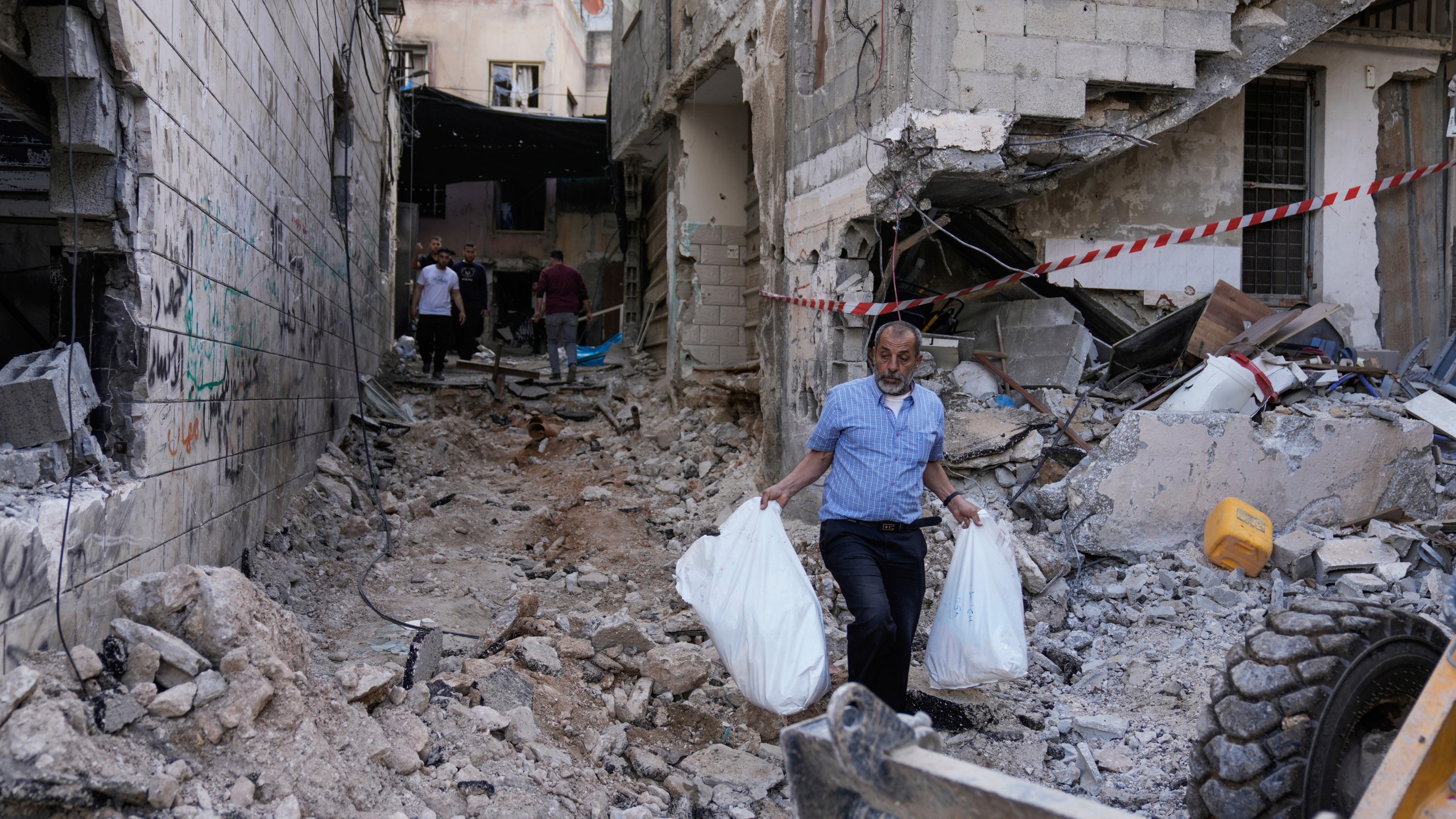 Palestinians walk on a damaged road following an Israeli military raid in Nur Shams refugee camp, near the West Bank town of Tulkarem, Sunday, April 21, 2024. The Palestinian Red Crescent rescue service said 14 bodies have been recovered from the Nur Shams urban refugee camp since an Israeli military operation began in the area Thursday night. The Islamic Jihad militant group confirmed the deaths of three members. Another killed was a 15-year-old boy. The Israeli army said its forces killed 10 militants in the camp and surrounding areas while eight suspects were arrested. (AP Photo/Majdi Mohammed)