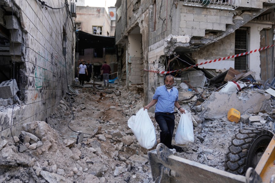 Palestinians walk on a damaged road following an Israeli military raid in Nur Shams refugee camp, near the West Bank town of Tulkarem, Sunday, April 21, 2024. The Palestinian Red Crescent rescue service said 14 bodies have been recovered from the Nur Shams urban refugee camp since an Israeli military operation began in the area Thursday night. The Islamic Jihad militant group confirmed the deaths of three members. Another killed was a 15-year-old boy. The Israeli army said its forces killed 10 militants in the camp and surrounding areas while eight suspects were arrested. (AP Photo/Majdi Mohammed)