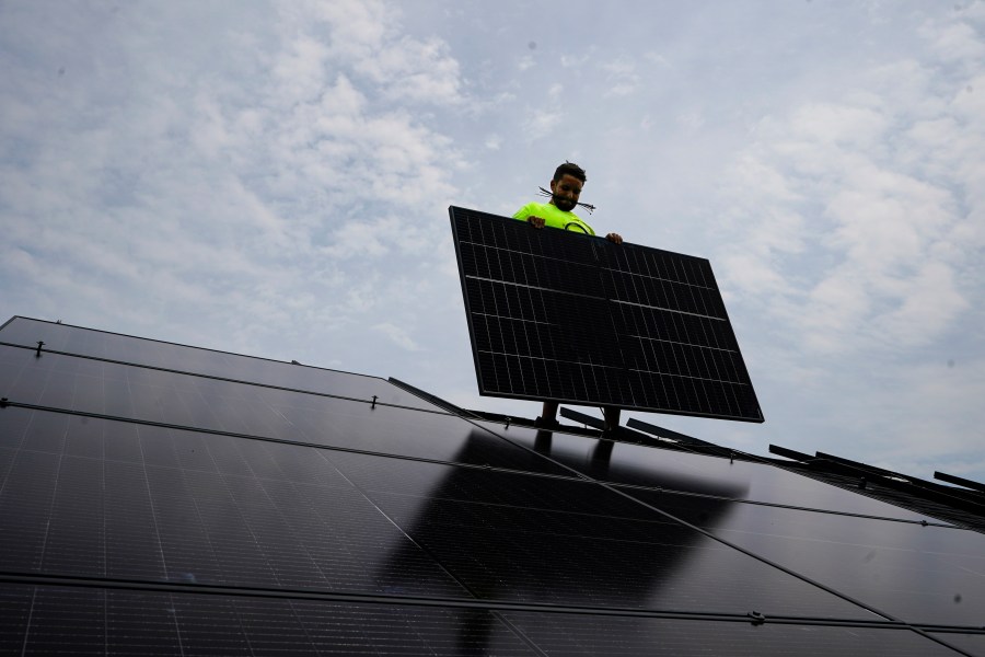 FILE - Nicholas Hartnett, owner of Pure Power Solar, holds a panel as his company installs a solar array on the roof of a home in Frankfort, Ky., July 17, 2023. (AP Photo/Michael Conroy, File)