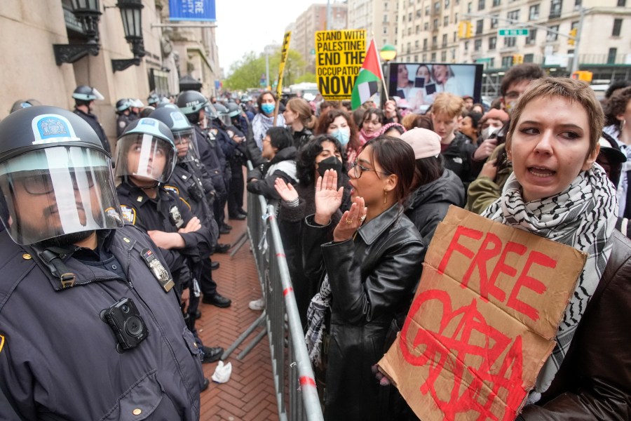 FILE - Police in Riot gear stand guard as demonstrators chant slogans outside the Columbia University campus, Thursday, April 18, 2024, in New York. U.S. colleges and universities are preparing for end-of-year commencement ceremonies with a unique challenge: providing safety for graduates while honoring the free speech rights of students involved in protests over the Israel-Hamas war. (AP Photo/Mary Altaffer, File)