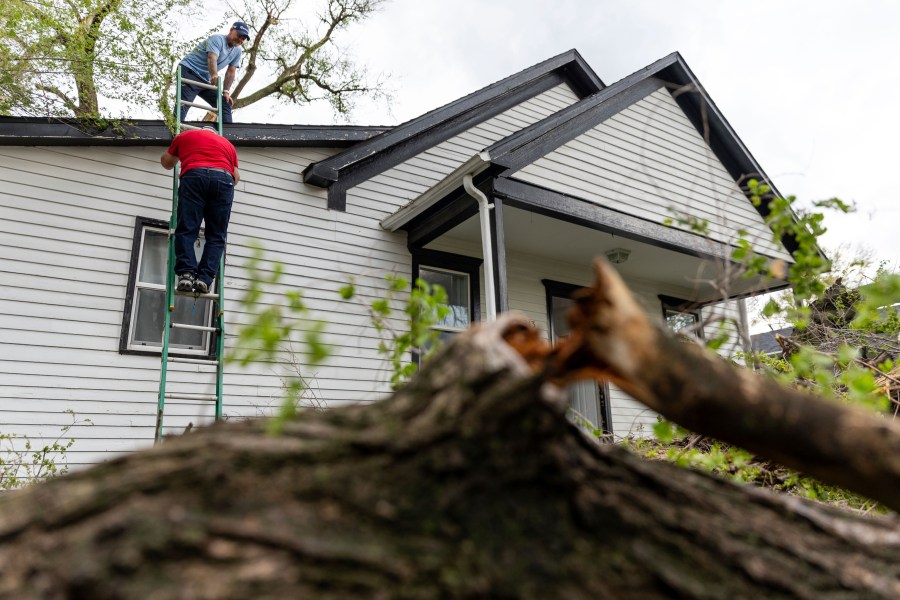 Robert Keesee helps his father, Randy Keesee, up a ladder to access roof damage to their home after a severe storm hit the neighborhood in Council Bluffs, Iowa, on Friday, April 26, 2024. (Anna Reed/Omaha World-Herald via AP)