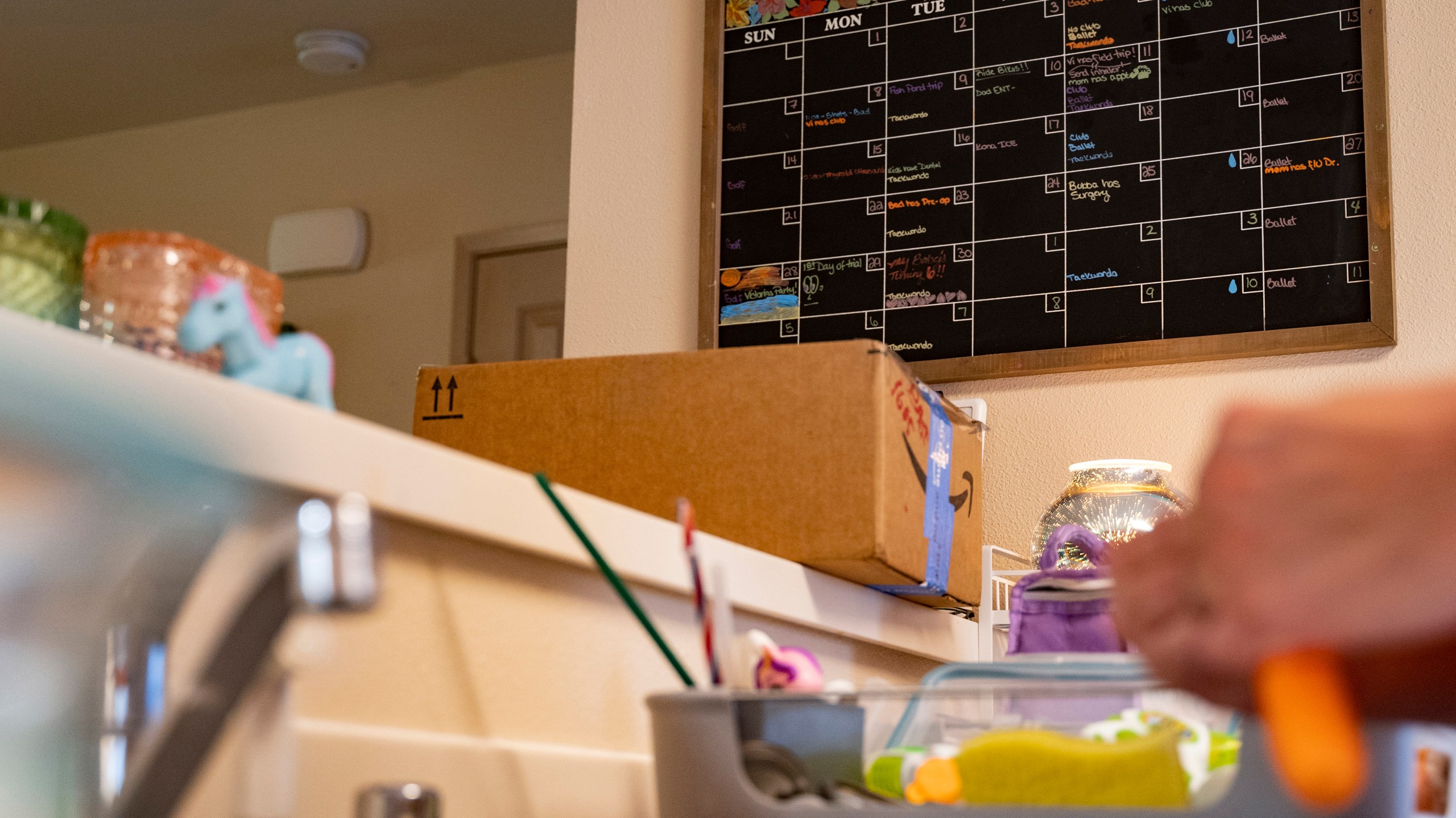 Richelle Dietz marks a water symbol on their calendar to denote the dates of their bi-weekly water delivery, Monday, April 22, 2024, in Honolulu, Hawaii. The Dietz family relies on these deliveries for basic needs since their water was tainted in 2021. (AP Photo/Mengshin Lin)