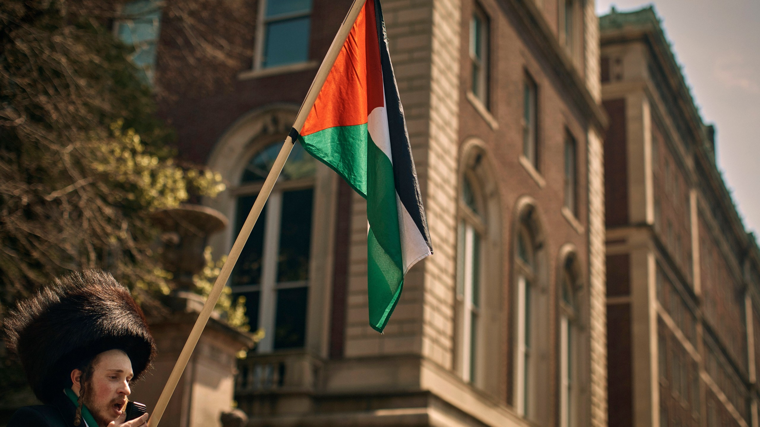 An Ultra-Orthodox Jewish man holds a Palestinian flag in support of the pro-Palestinian encampment, advocating for financial disclosure and divestment from all companies tied to Israel and calling for a permanent cease-fire in Gaza, outside Columbia University campus on Sunday, April 28, 2024, in New York. (AP Photo/Andres Kudacki)