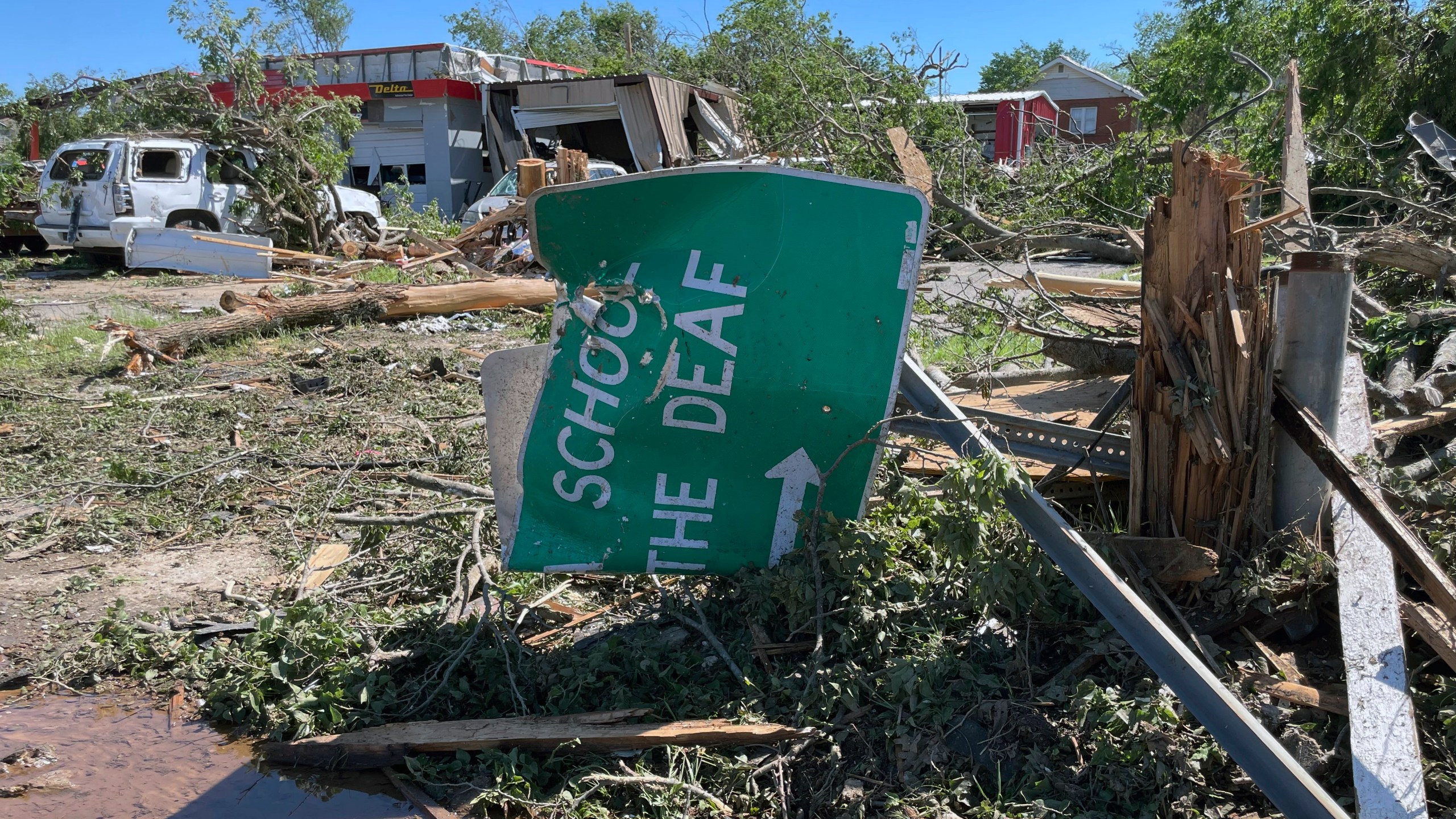 A sign for the Oklahoma School for the Deaf, lies crumpled and twisted near downtown Sulphur, Oklahoma, Monday, April 29, 2024. (AP Photo/Graham Brewer)