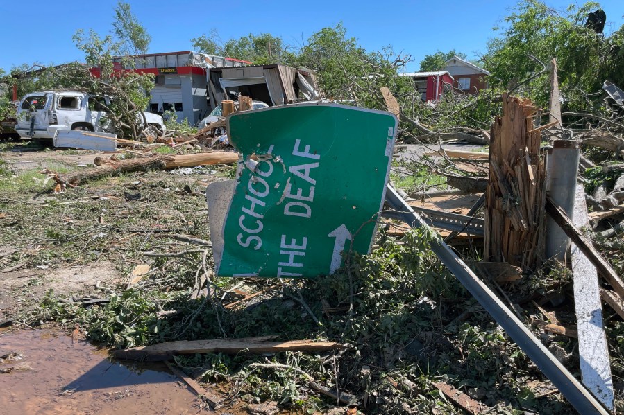 A sign for the Oklahoma School for the Deaf, lies crumpled and twisted near downtown Sulphur, Oklahoma, Monday, April 29, 2024. (AP Photo/Graham Brewer)