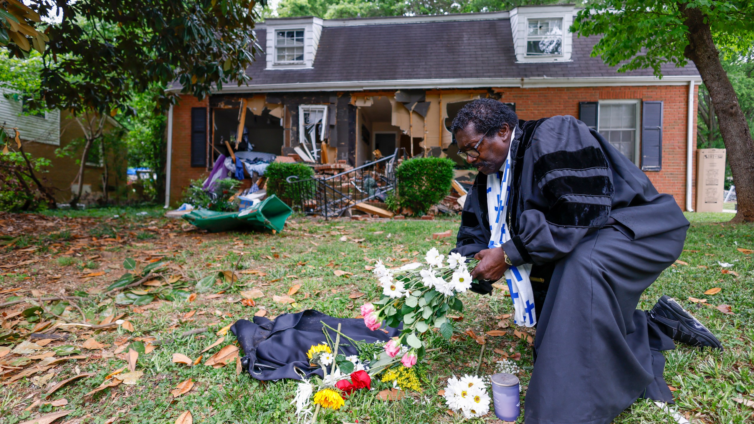 Rev. Raymond Johnson, of Marion, S.C., arranges flowers on the lawn of the home on Galway Drive in Charlotte, N.C., Tuesday, April 30, 2024 where a shootout between a suspect and officers occurred during an attempt to serve a warrant on Monday. Four law enforcement officers were killed. (AP Photo/Nell Redmond)