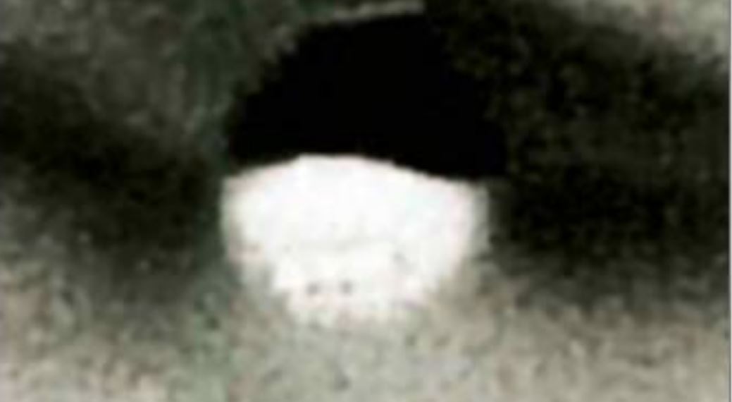 A blurry object in black and white, lighter on the bottom and darker on top.