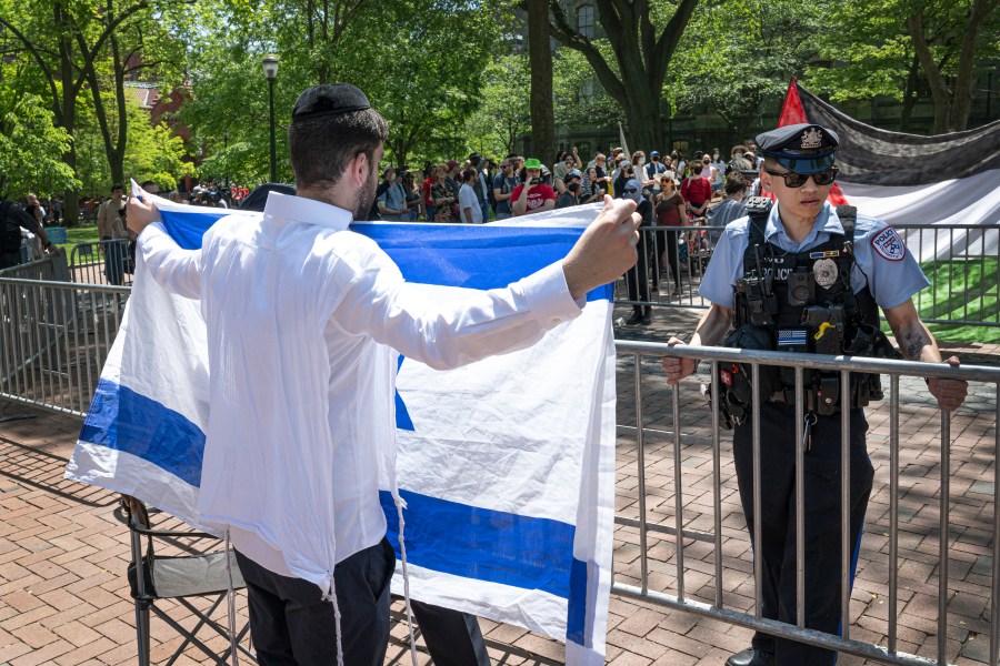 A pro-Israel supporter waves the Israeli flag in front of a police officer and a pro-Palestinian camp at the University of Pennsylvania encampment Thursday, May 2, 2024, in Philadelphia. (Jose F. Moreno/The Philadelphia Inquirer via AP)