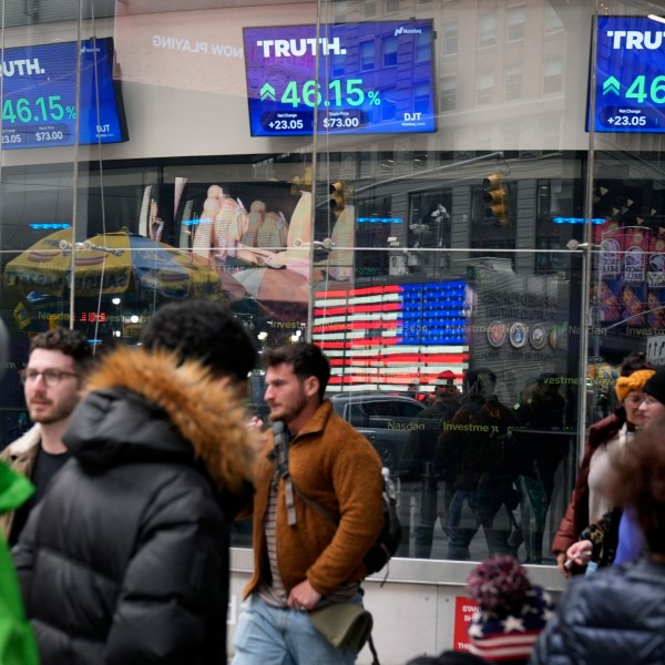 FILE - Pedestrians walk past the Nasdaq building as the stock price of Trump Media & Technology Group Corp. is displayed on screens, March 26, 2024, in New York. An auditing firm hired by Trump Media and Technology Group just 37 days ago was busted by the Securities and Exchange Commission for “massive fraud” — though not for any work it performed for former President Donald Trump’s media company. (AP Photo/Frank Franklin II, File)