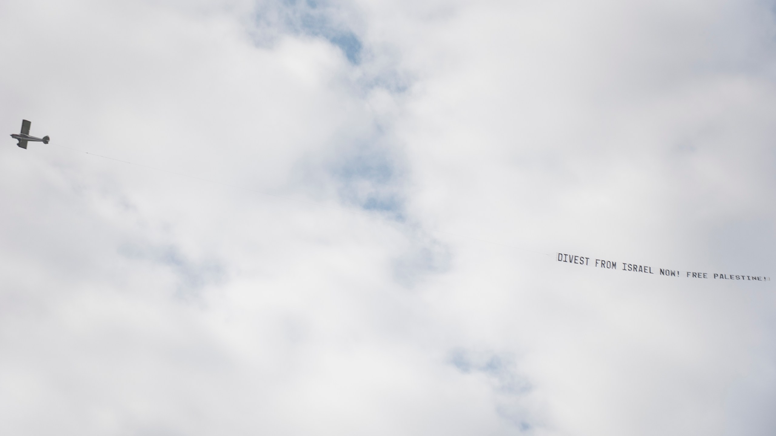 CORRECTS PHRASE ON BANNER - A plane pulling a banner that reads "Divest From Israel Now! Free Palestine" flies overhead before the University of Michigan's Spring 2024 Commencement Ceremony at Michigan Stadium in Ann Arbor, Mich., on Saturday, May 4, 2024. (Katy Kildee/Detroit News via AP)