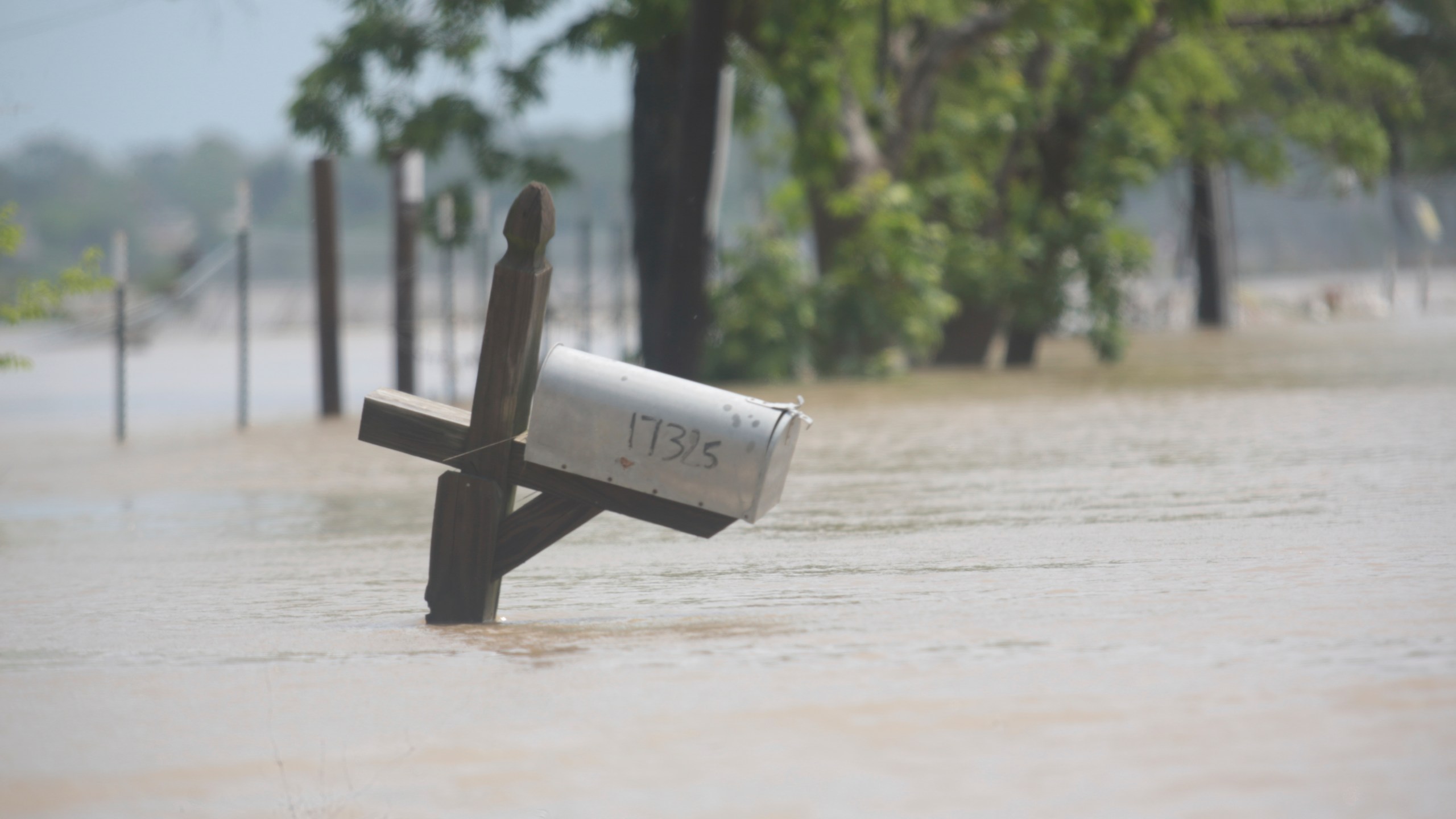 A mailbox is partially submerged on a flooded street in an unincorporated area in east Harris County near Houston on Sunday morning, May 5, 2024. The nearby San Jacinto River, overflowing due to heavy rainfall earlier this week, caused the flood waters. (AP Photo/Lekan Oyekanmi)