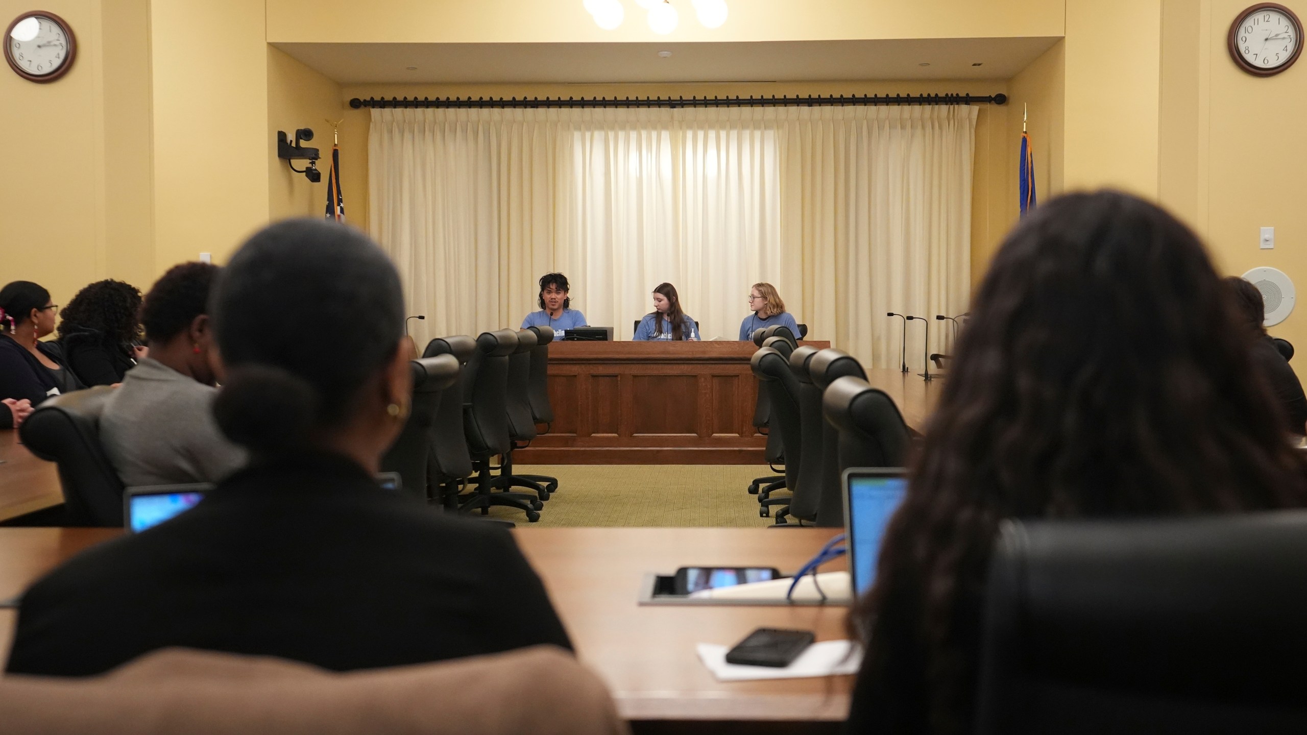 B Rosas, back left, Lucia Everist, back center, and Libby Kramer, back right, of Climate Generation, speak to the Minnesota Youth Council, Tuesday, Feb. 27, 2024, in St. Paul, Minn. The advocates called on the council, a liaison between young people and state lawmakers, to support a bill requiring schools to teach more about climate change. (AP Photo/Abbie Parr)