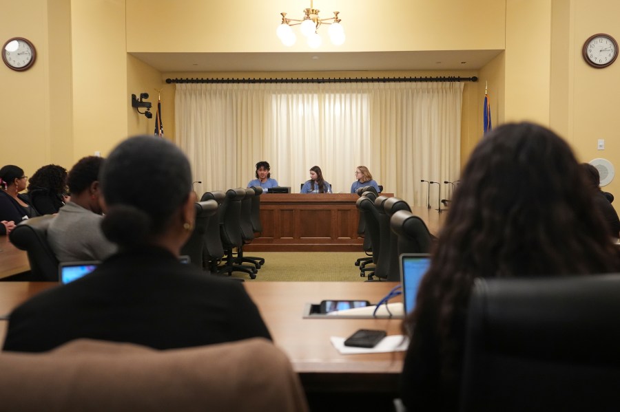 B Rosas, back left, Lucia Everist, back center, and Libby Kramer, back right, of Climate Generation, speak to the Minnesota Youth Council, Tuesday, Feb. 27, 2024, in St. Paul, Minn. The advocates called on the council, a liaison between young people and state lawmakers, to support a bill requiring schools to teach more about climate change. (AP Photo/Abbie Parr)