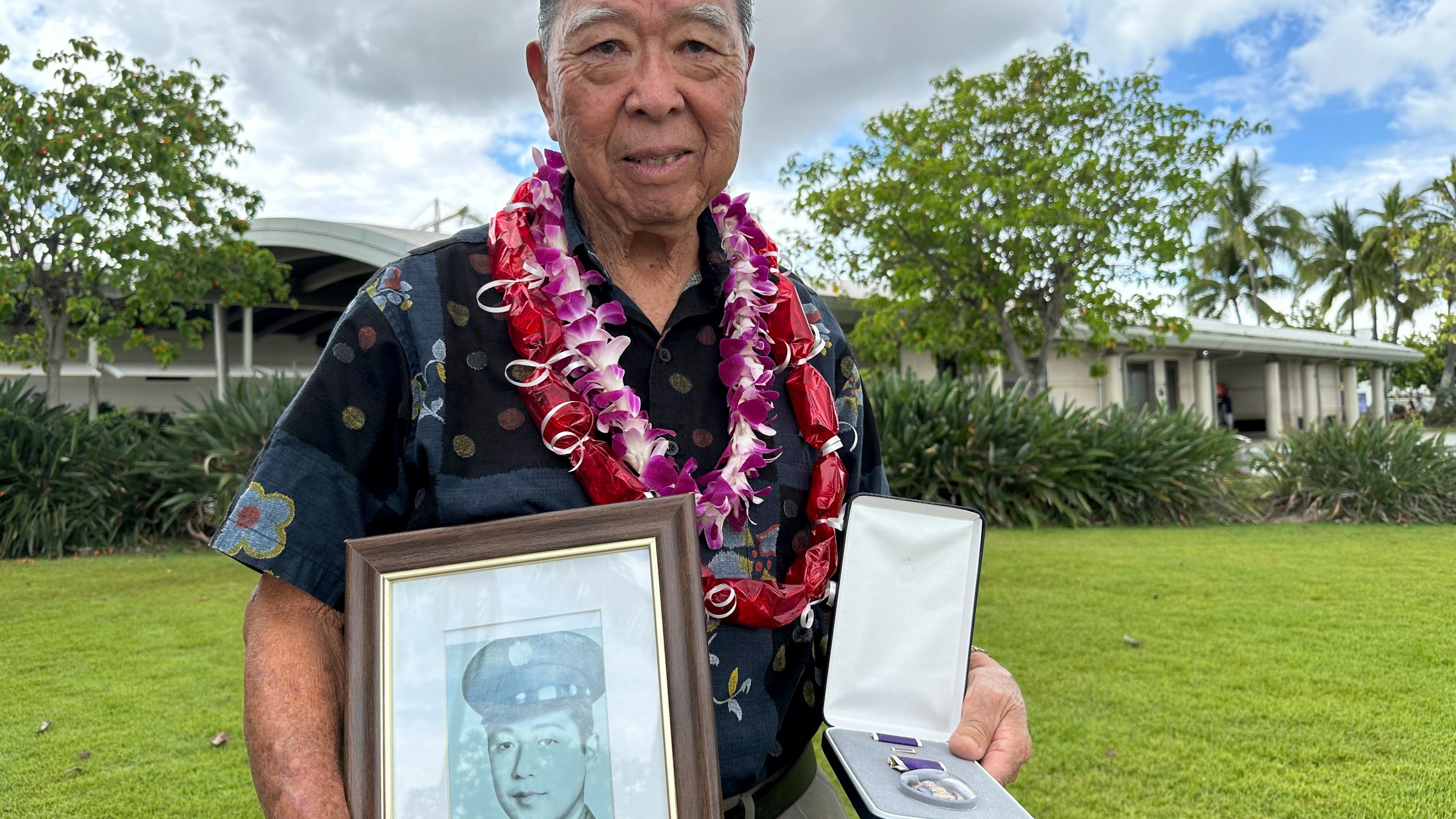 Wilfred Ikemoto holds a photo of his older brother, Haruyuki Ikemoto, and the Purple Heart medal posthumously awarded to him, in Pearl Harbor, Hawaii, on Friday, May 10, 2024. The families of five Hawaii men who served in a unit of Japanese-language linguists during World War II received posthumous Purple Heart medals on behalf of their loved ones on Friday, nearly eight decades after the soldiers died in a plane crash in the final days of the conflict. (AP Photo/Audrey McAvoy)