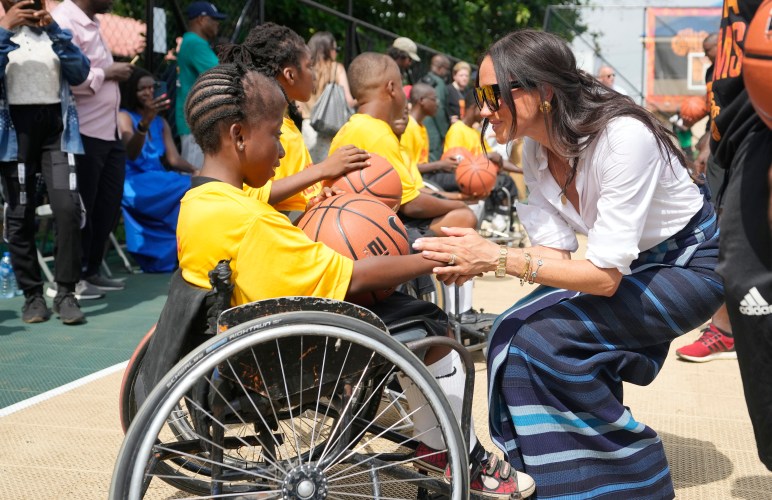 Meghan Markle, right, shake hands with a girl on a wheelchair during the Giant of Africa Foundation at the Dream Big Basketball clinic in Lagos Nigeria, Sunday, May 12, 2024. Prince Harry and his wife Meghan are in Nigeria to champion the Invictus Games, which Prince Harry founded to aid the rehabilitation of wounded and sick servicemembers and veterans. (AP Photo/Sunday Alamba)