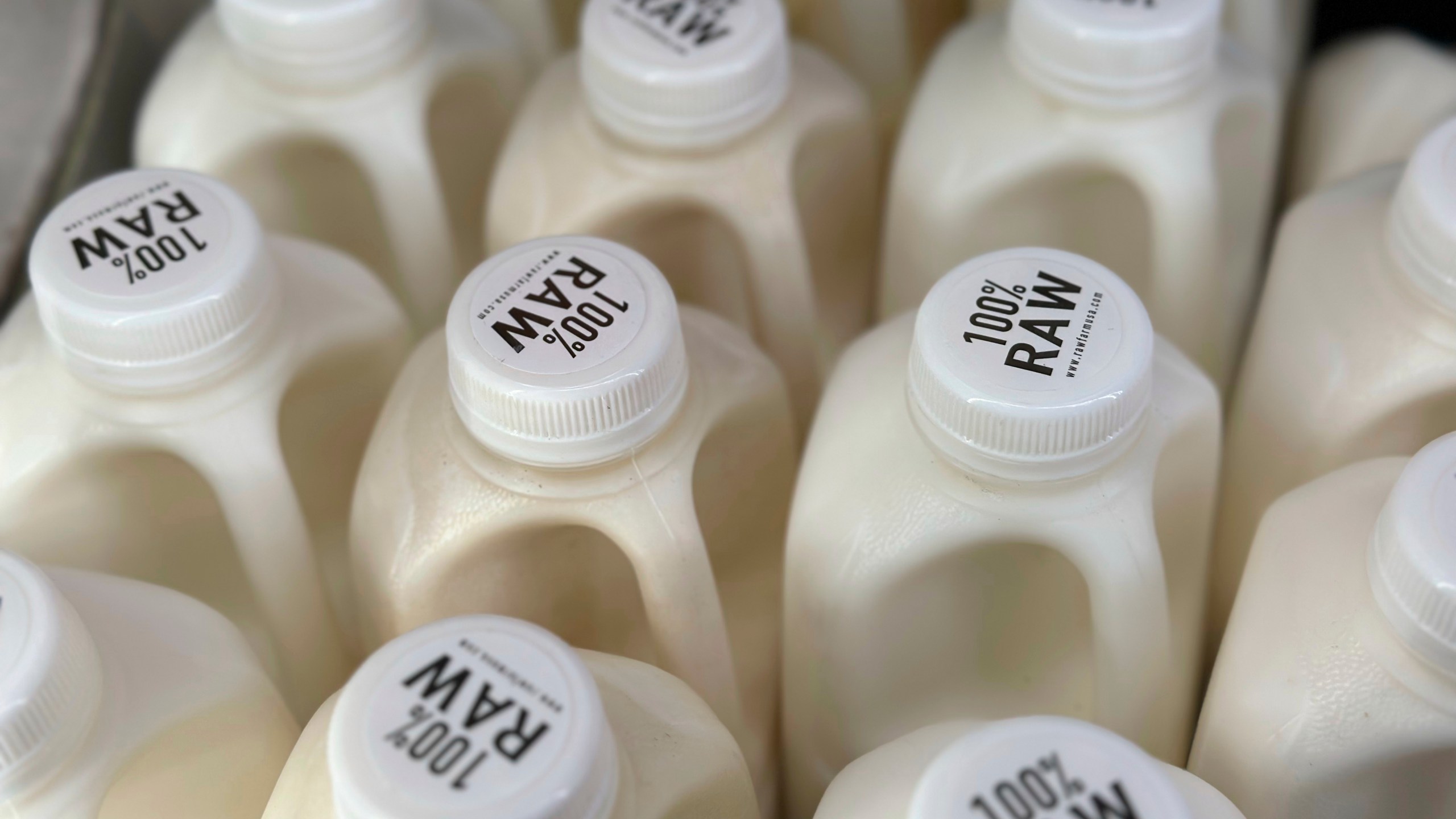 Bottles of raw milk are displayed for sale at a store.