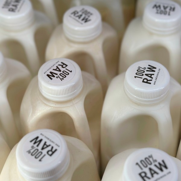 Bottles of raw milk are displayed for sale at a store.