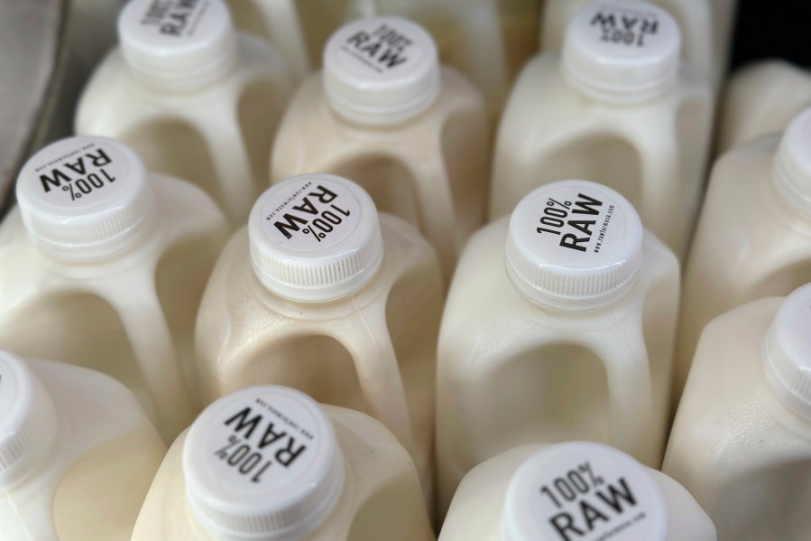 Bottles of raw milk are displayed for sale at a store.