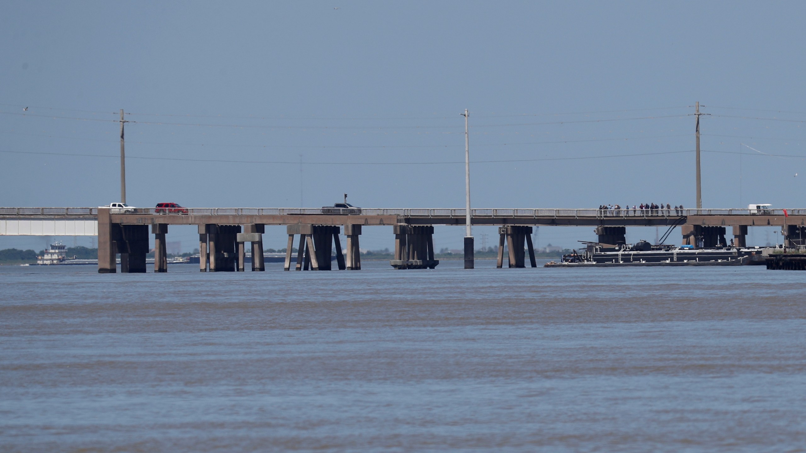 A tugboat works to maneuver a barge away from the Pelican Island Bridge in Galveston, Texas, on Wednesday, May 15, 2024, after the barge crashed into the bridge spilling oil into surrounding waters and shutting down the only road access to and from the island. (Jennifer Reynolds/The Galveston County Daily News via AP)