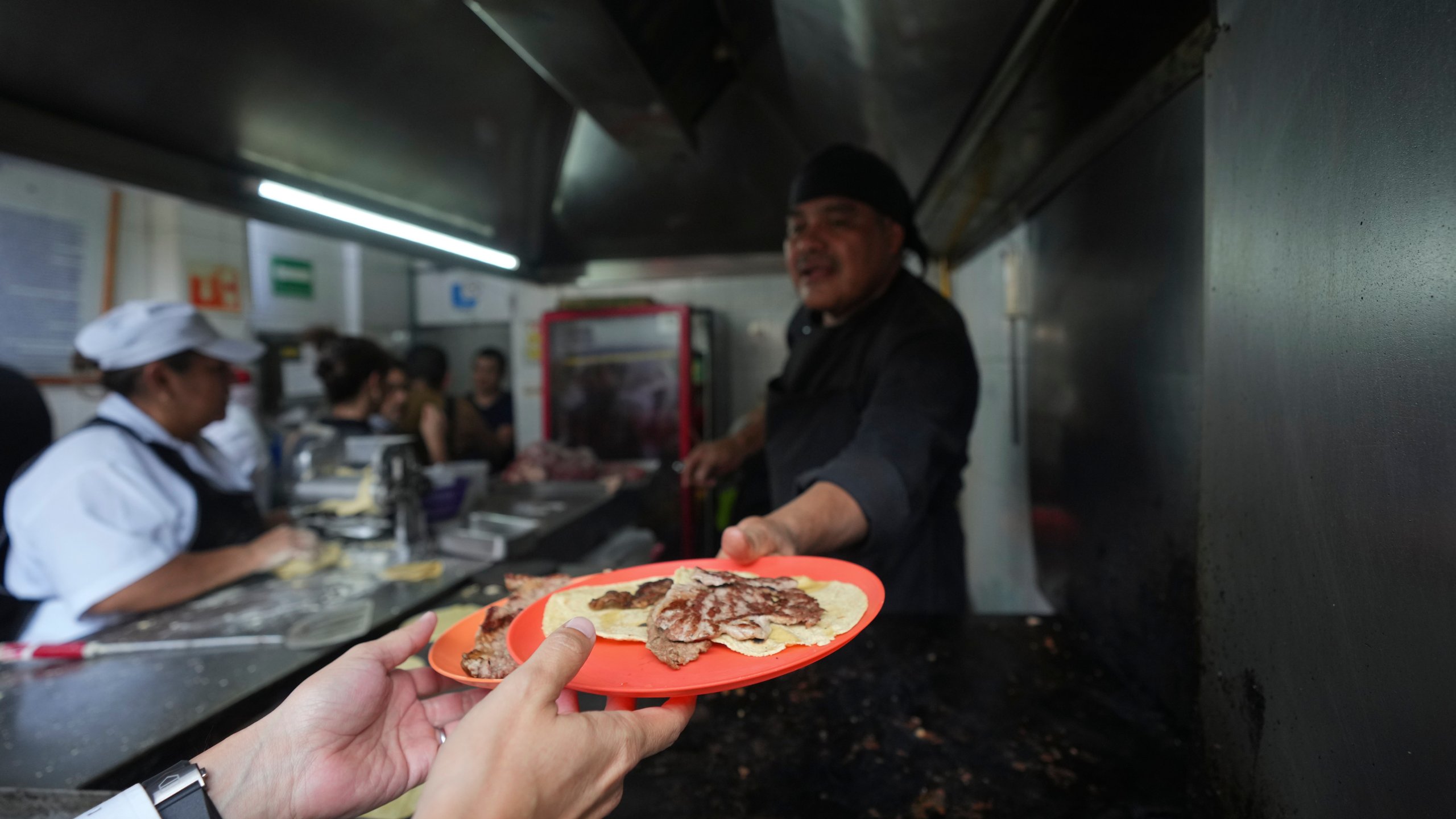 Newly minted Michelin-starred chef Arturo Rivera Martínez hands a customer his order of tacos at the Tacos El Califa de León taco stand, in Mexico City, Wednesday, May 15, 2024. Tacos El Califa de León is the first ever taco stand to receive a Michelin star from the French dining guide. (AP Photo/Fernando Llano)