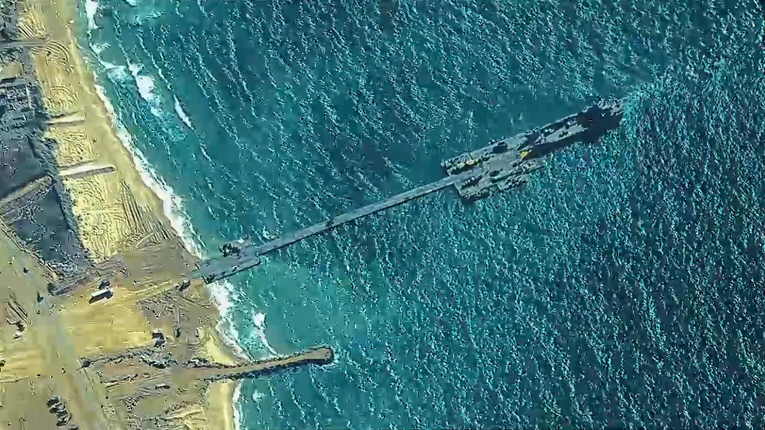 The image provided by U.S, Central Command, shows U.S. Army soldiers assigned to the 7th Transportation Brigade (Expeditionary), U.S. Navy sailors assigned to Amphibious Construction Battalion 1, and Israel Defense Forces placing the Trident Pier on the coast of Gaza Strip on Thursday, May 16, 2024. The temporary pier is part of the Joint Logistics Over-the-Shore capability. The U.S. military finished installing the floating pier on Thursday, with officials poised to begin ferrying badly needed humanitarian aid into the enclave besieged over seven months of intense fighting in the Israel-Hamas war. (U.S. Central Command via AP)