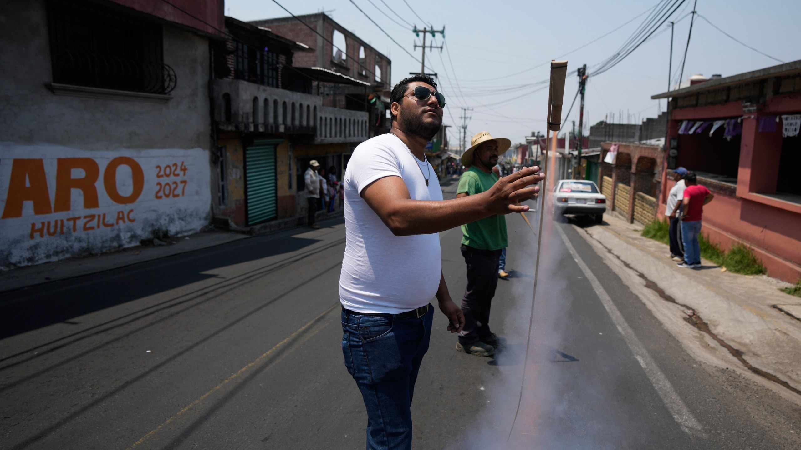 A resident sets off a firework during a funeral service for four men slain in a mass shooting, in Huitzilac, Mexico, Tuesday, May 14, 2024. The shooting in the mountain township beset by crime just south of Mexico City resulted in several deaths, authorities said Sunday. (AP Photo/Fernando Llano)