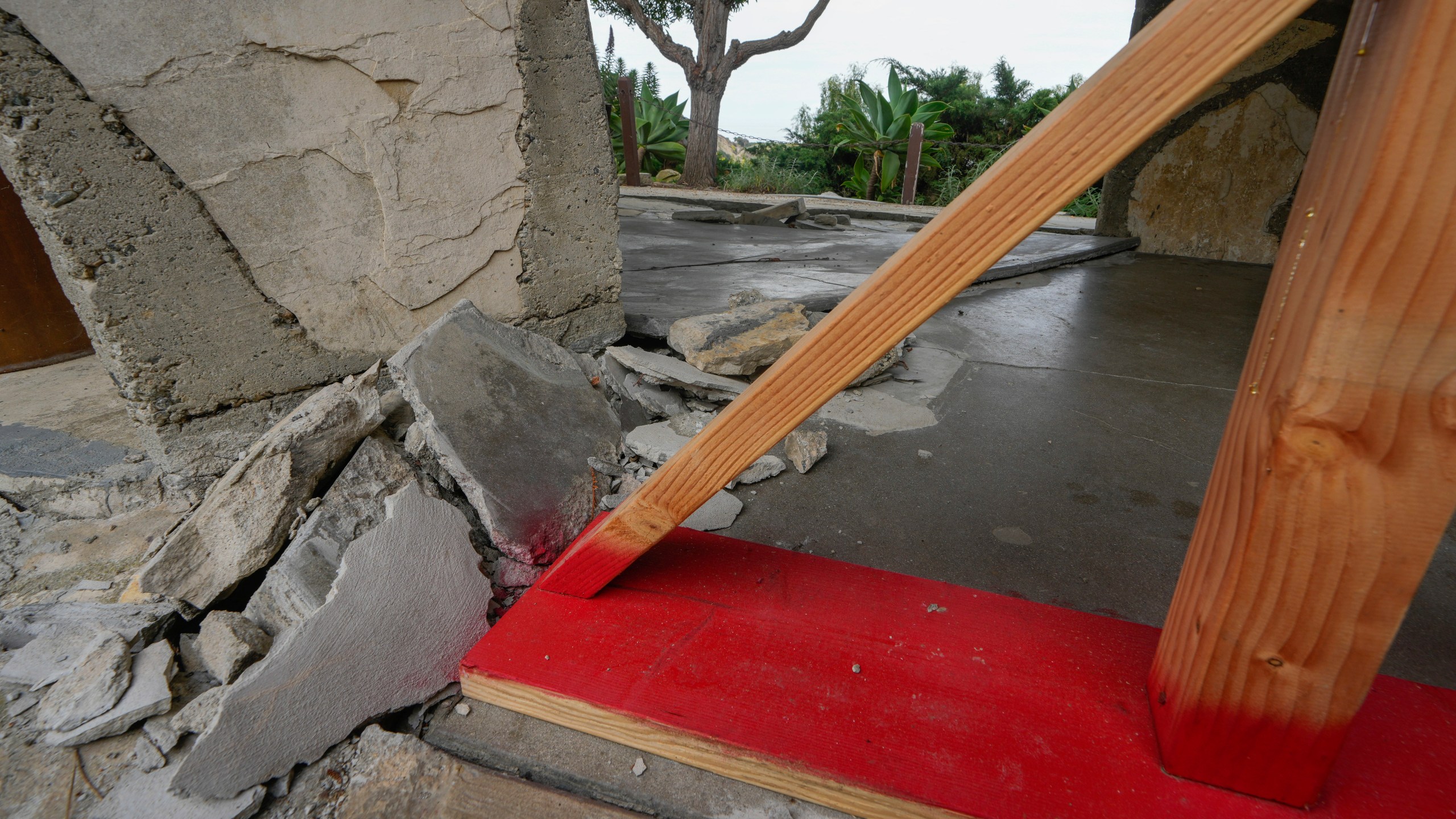 A wood base supports the tilting walls of a hall leading to Wayfarers Chapel, also known as "The Glass Church," in Rancho Palos Verdes, Calif., Wednesday, May 15, 2024. The famed cliffside location on the Palos Verdes Peninsula is also responsible for its downfall. While the Portuguese Bend landslide began in 1956, it's recently worsened, and chapel officials say the earth underneath "The Glass Church" and its surrounding area is now moving an unprecedented 2 feet (0.61 meters) or more each month. (AP Photo/Damian Dovarganes)