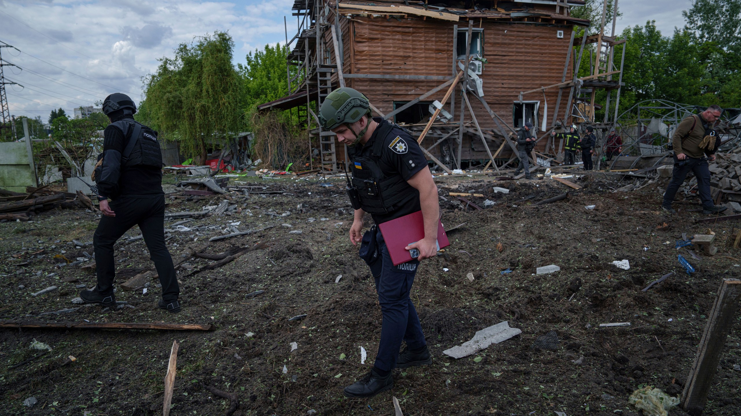 Ukrainian police officers look for fragments of a glide bomb in front of damaged house after a Russian airstrike on a residential neighbourhood in Kharkiv, Ukraine, Saturday, May 18, 2024. (AP Photo/Evgeniy Maloletka)